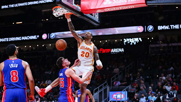 John Collins dunks over Detroit Pistons defnders.